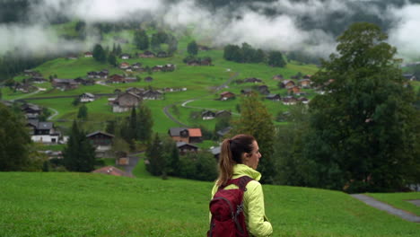 woman backpacker hikes into the swiss alpine village of wengen