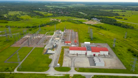 aerial drone footage spinning and orbiting around at a high altitude over a electrical power station or a substation in a rural countryside with lots of electrical lines running to and from it, summer