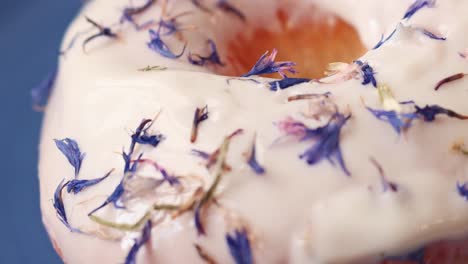 donut with white icing and edible blue flower sprinkle close up