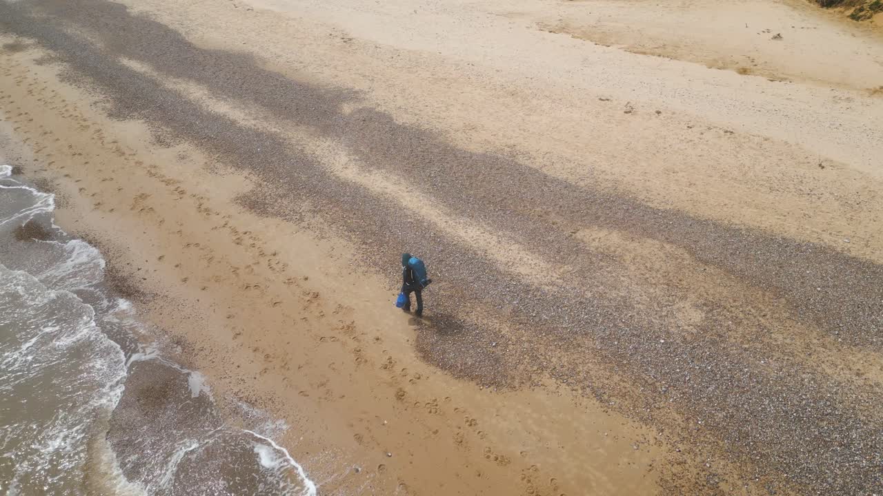 un turista con mochila explorando la playa de kessingland durante un día soleado en suffolk, inglaterra