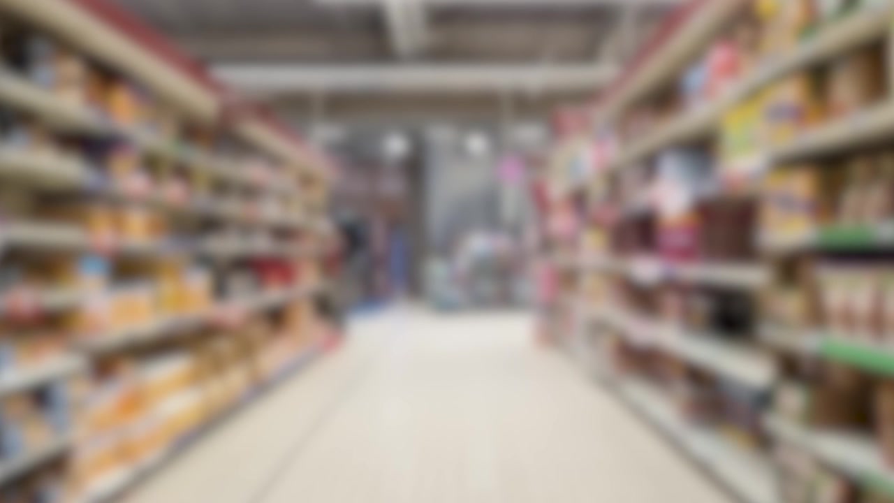 A smooth tracking shot moves forward through a blurred supermarket aisle with stocked food shelves