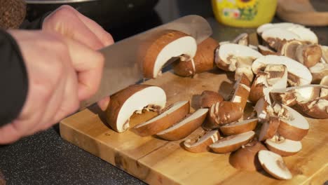 close up of fresh mushrooms being sliced by a woman hand preparing a healthy recipe