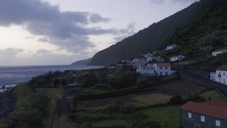 rural coastal village in lush green cliffs on blue hour, fajã dos vimes, são jorge island, the azores, portugal