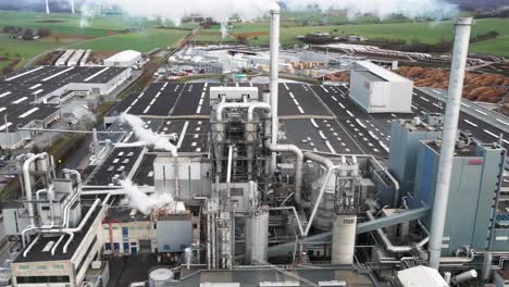 aerial view of polluting wood processing factory in germany: smoke from production process filling the atmosphere at plant manufacturing yard