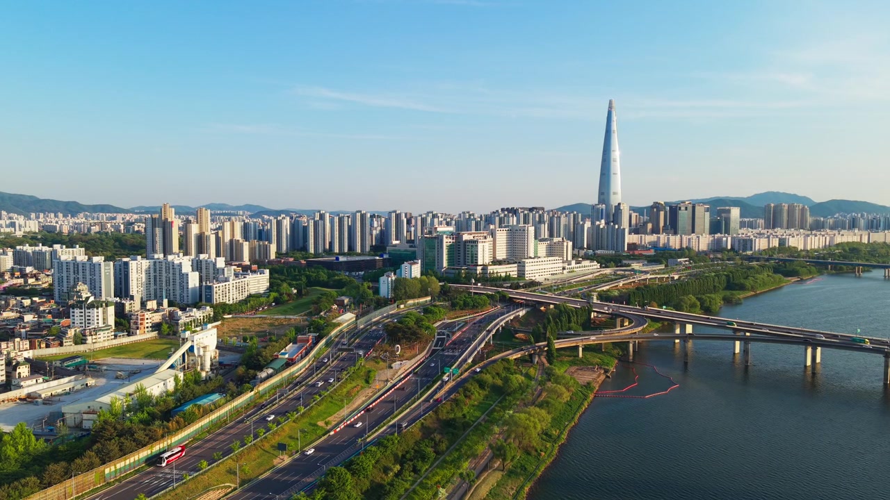 Vista aerea del traffico sull'autostrada Olympic-daero vicino al ponte Olimpico, con il grattacielo Lotte World Tower e appartamenti moderni, in una giornata primaverile soleggiata e limpida a Seul, Corea del Sud.