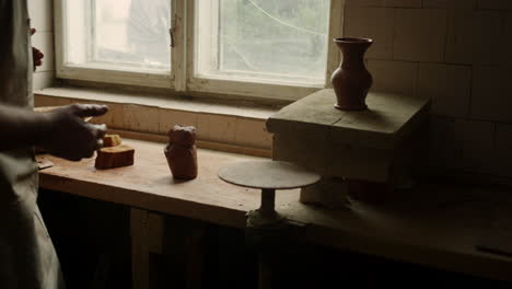 unknown master putting freshmade clay jar on board. artist finishing clay jar