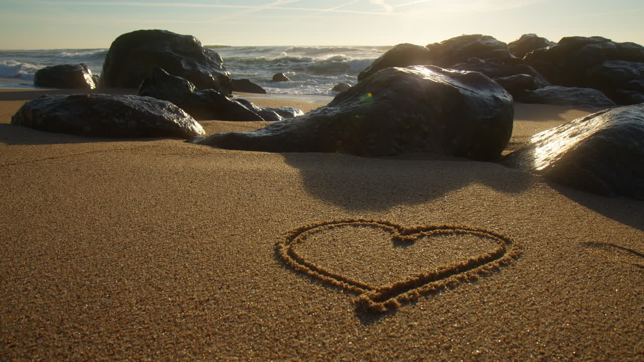 Beautiful heart drawn in the sand of a beach at sunset. Close up