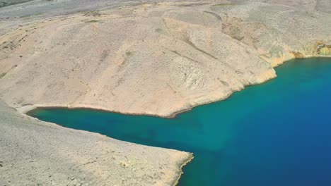 El-Agua-Turquesa-Del-Océano-Se-Encuentra-Con-La-Tierra-Rocosa-De-La-Isla-De-Pag,-Croacia