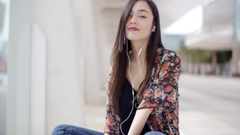 Trendy-young-woman-listening-to-music-in-town