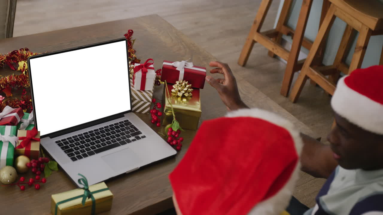 pareja diversa con sombreros de santa teniendo llamada de video portátil con espacio de copia