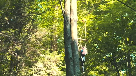 woman travelling downwards through the forest, enjoying a thrill ride with zip wires in signal de bougy parc adventure, slow motion footage