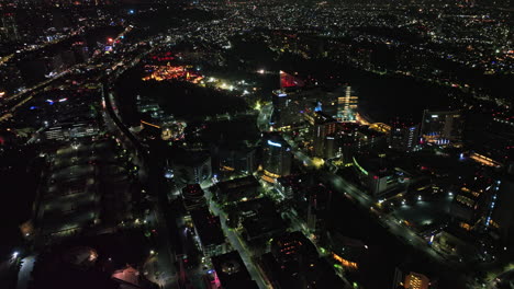 Mexico-City-Aerial-v56-tilt-down-descending-shot-of-night-cityscape-in-santa-fe-neighborhood,-capturing-illuminated-luxury-hotels-facade-and-street-traffic---Shot-with-Mavic-3-Cine---January-2022