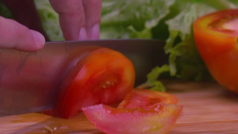 close up of a chefs hands using a knife to slice a juicy tomato