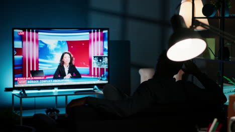 relaxed person watching breaking news on television at night