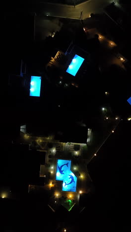vertical birds eye drone shot over illuminated holiday villas, night in greece