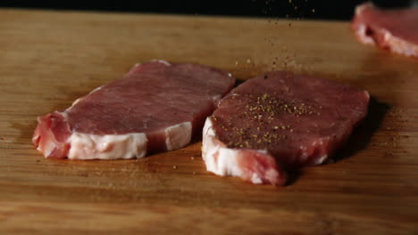las chuletas de cerdo son sazonadas en una mesa de madera