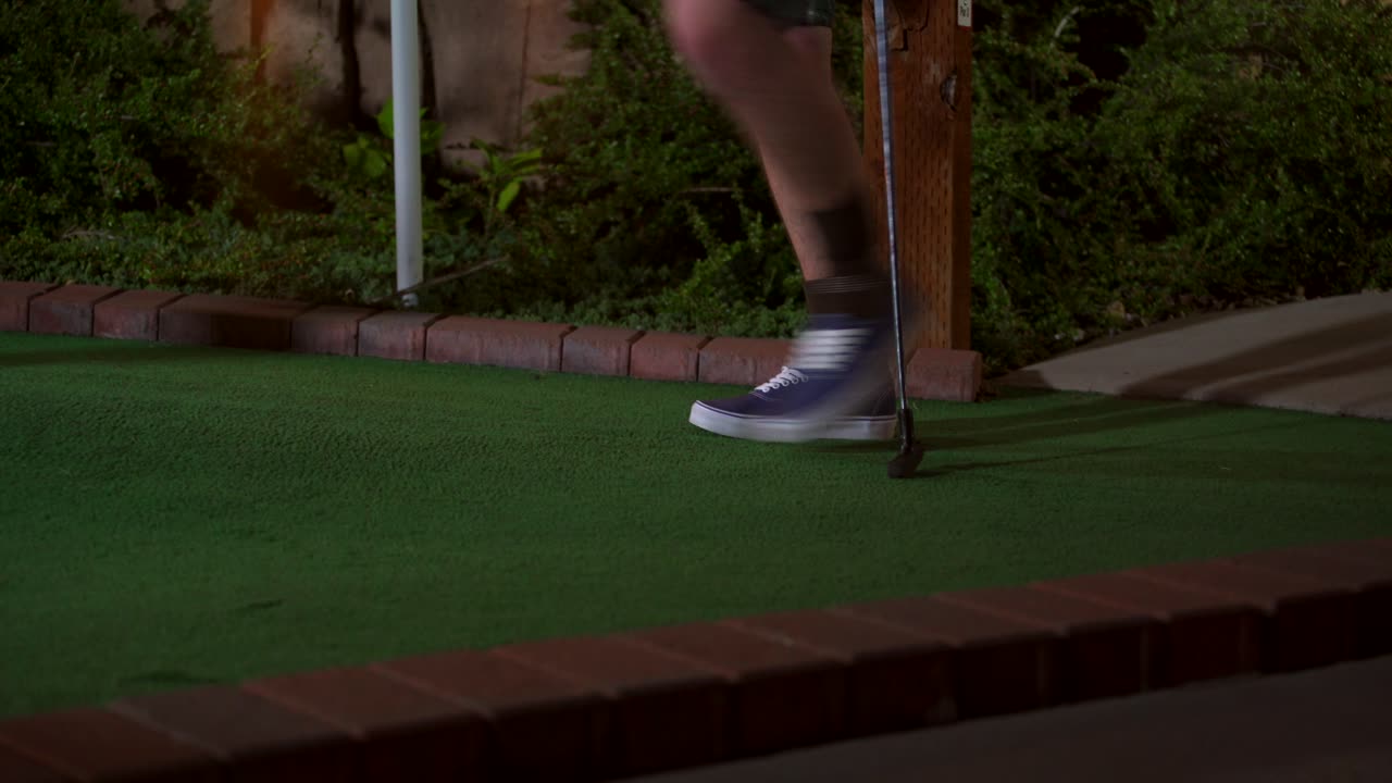 un primer plano de una mini pelota de golf morada siendo golpeada con un palo