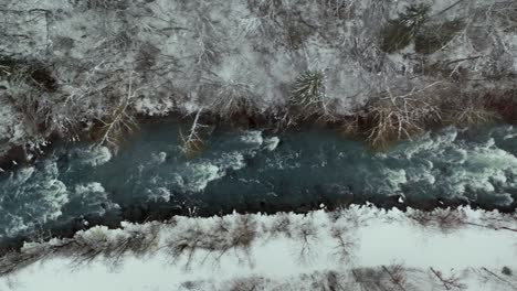 Increíble-Escena-Del-Río-De-Invierno-Que-Fluye-Por-La-Ladera-Nevada,-Vista-Aérea-De-Arriba-Hacia-Abajo