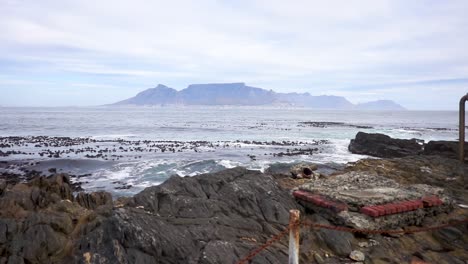 slomo tilt up of table mountain in the far distance with the ocean in front