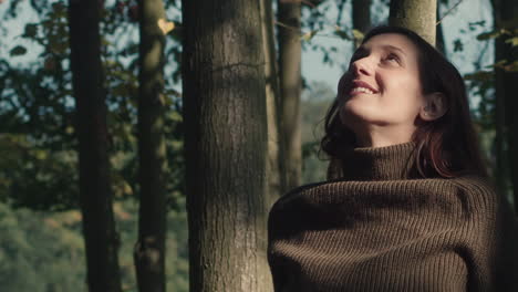 woman watches the leaves fall from the trees on a beautiful sunny autumn day