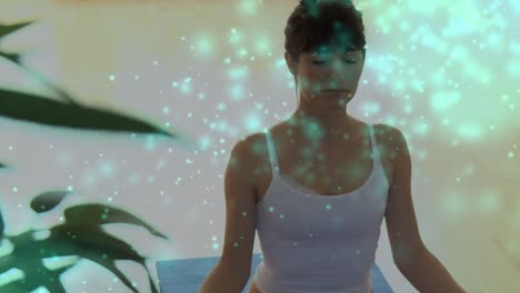 animation of light spots over caucasian woman practicing yoga and meditating