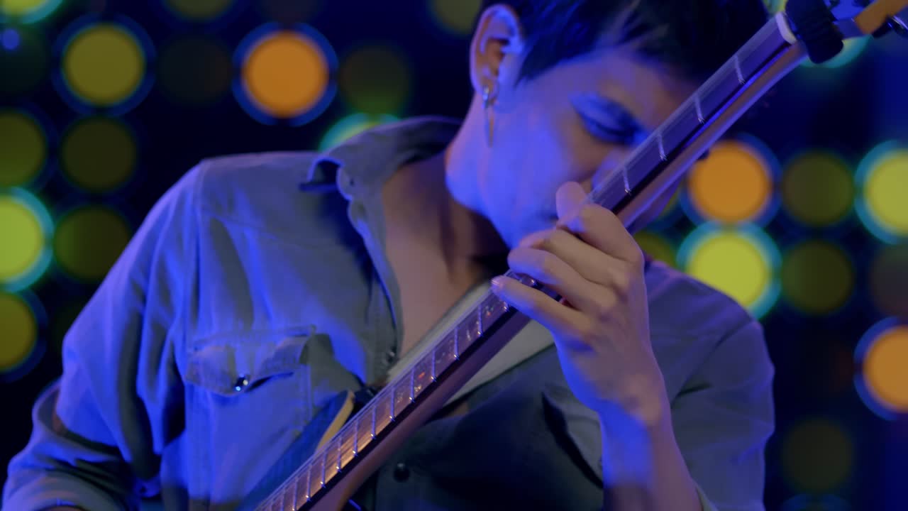 열정으로 고개를 끄덕이며 기타를 연주하는 음악가의 슬로우 모션 샷
