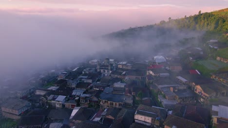 Nebel,-Der-Während-Des-Hellen-Sonnenuntergangs-Oder-Sonnenaufgangs-über-Einer-Kleinen-Stadt-Fließt,-Luftaufnahme