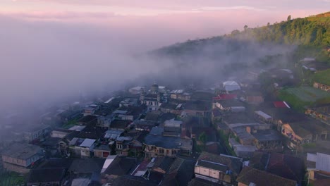 niebla que fluye sobre una pequeña ciudad durante el brillante atardecer del amanecer, vista aérea