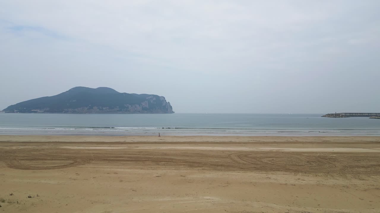 Wavy sea washing sandy coast under overcast sky in Cantabria, Spain