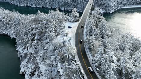 aerial view of cars driving over water with snow surrounding the land