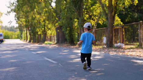rear view of a baby boy walking by the road. following an unrecognized kid outdoors in summer.