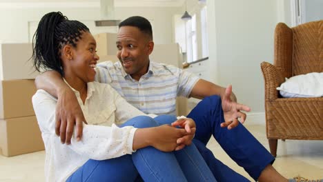 Vista-Frontal-De-Una-Feliz-Pareja-Joven-Negra-Sentada-En-El-Suelo-E-Interactuando-Entre-Sí-En-Casa-4k