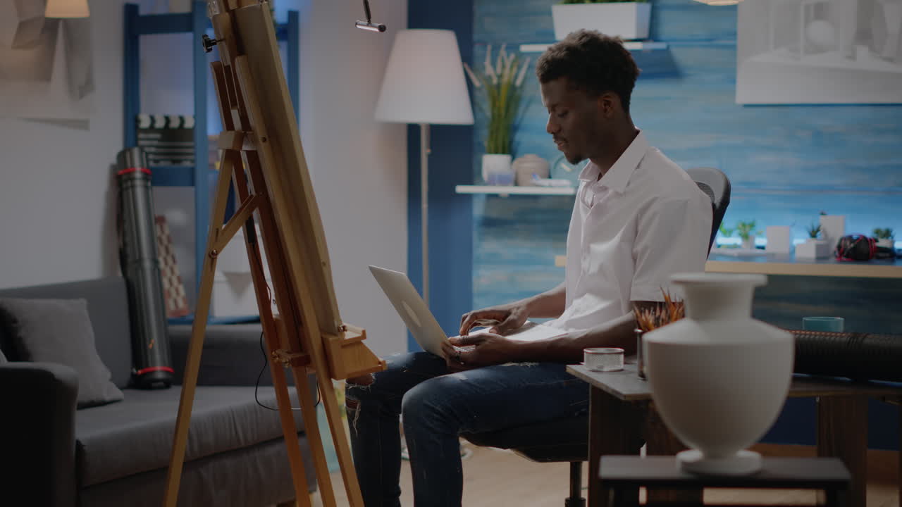 Artist of african american ethnicity typing on laptop