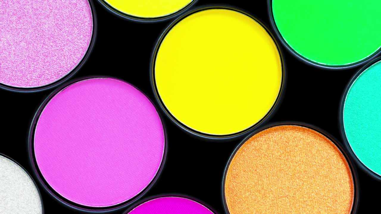multicolor hermosa paleta de sombra de neón en fondo negro. aislado. productos de belleza. cosméticos de maquillaje. sombra de ojos de verano. amarillo, rosa, verde. vista superior. animación de stop motion de colores brillantes.
