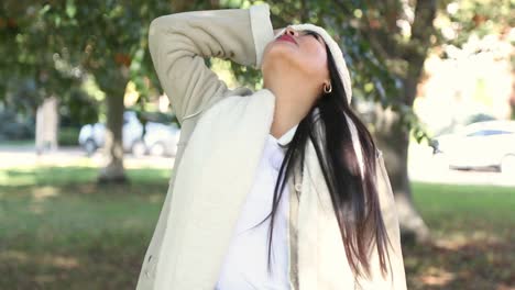 Hermosa-Chica-Mira-A-Su-Alrededor-Las-Frías-Hojas-De-Otoño-En-Un-Parque-De-La-Ciudad-Sonriendo-Con-Asombro