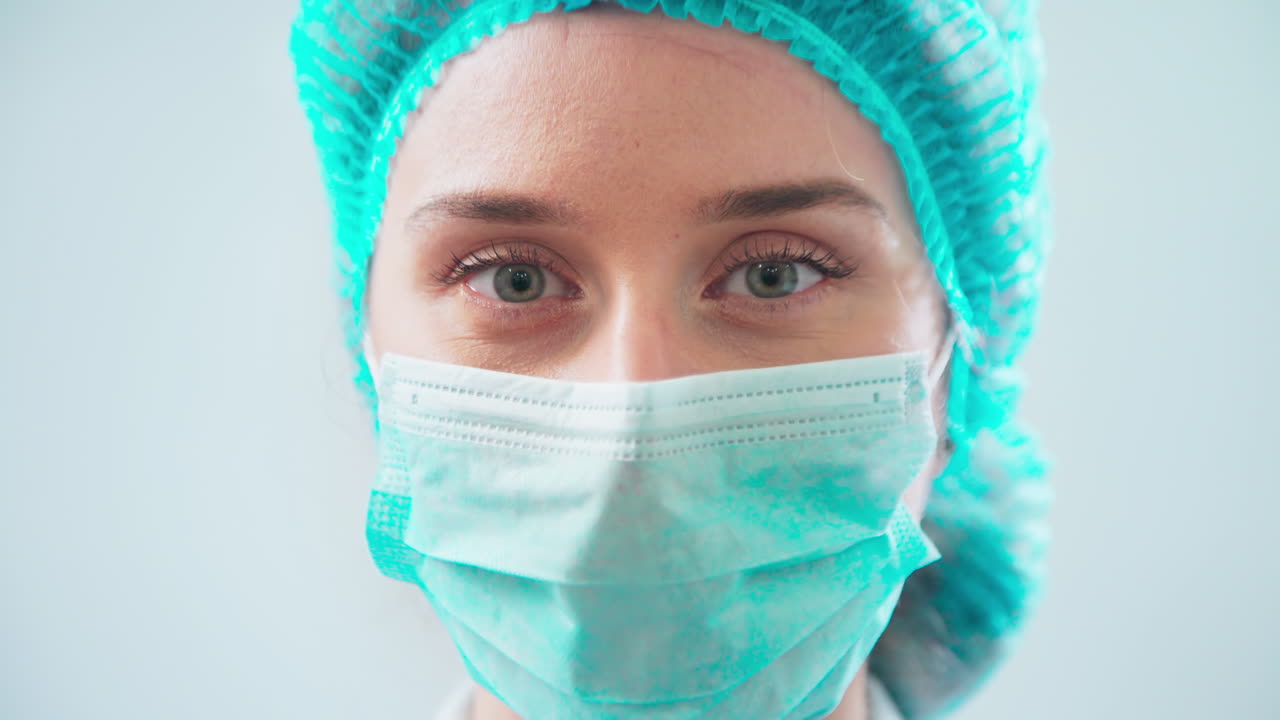 Doctor in medical hat taking off mask and smiling in the dental office looking into the camera