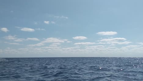 small private luzzu boat with people in life jackets traveling in beautiful blue open mediterranean sea with calm waves and scenic panorama view on a beautiful sunny day