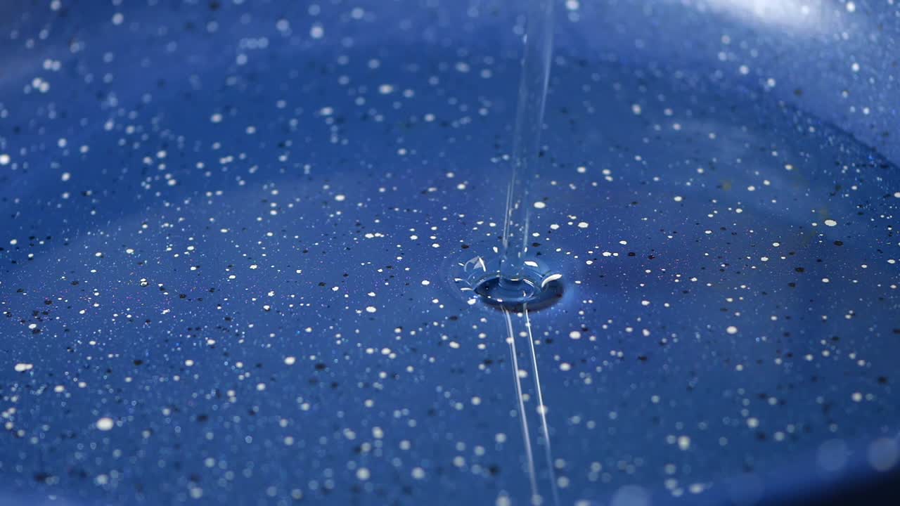Klare Flüssigkeit auf blau gesprenkelte Oberfläche gegossen