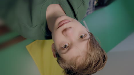 closeup portrait of an attractive teen boy sitting up in bed and looking at camera as camera rolls