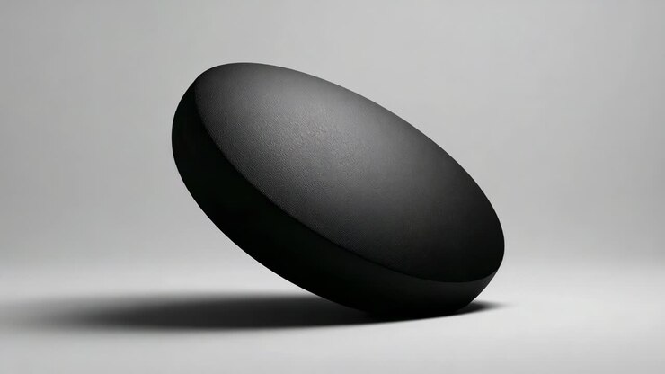 Rotating matte black disk after start tilt and hovering over gray floor, showing shadow and texture
