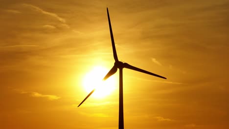 turbine silhouette spinning against a warm, golden sunset sky