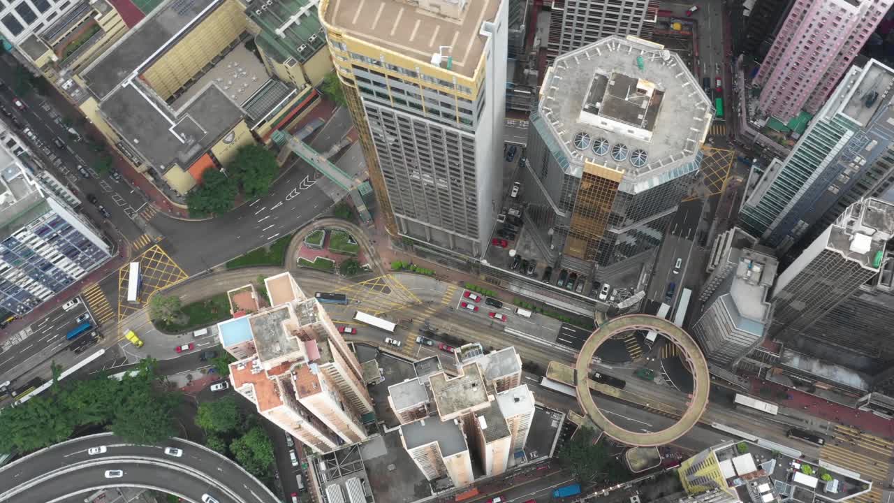 Aerial footage captures the dynamic Hong Kong skyline with towering skyscrapers, intricate roadways, and a bustling street life. The vibrant cityscape is enveloped in ambient daylight