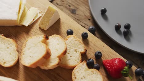 video de rebanadas de baguette, arándanos y queso en una superficie de madera