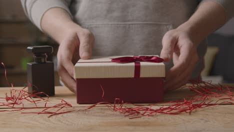 close up of man at home gift wrapping romantic valentines present in box