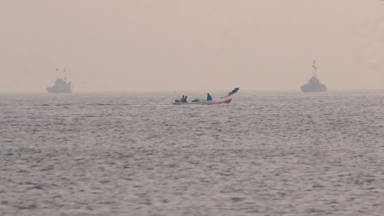 Two fisherman moving in small wooden boat in middle of the ocean in calm waves to collect fishes