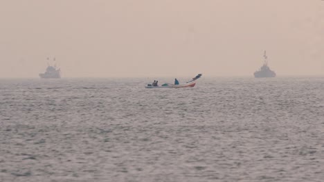 two fisherman moving in small wooden boat in middle of the ocean in calm waves to collect fishes