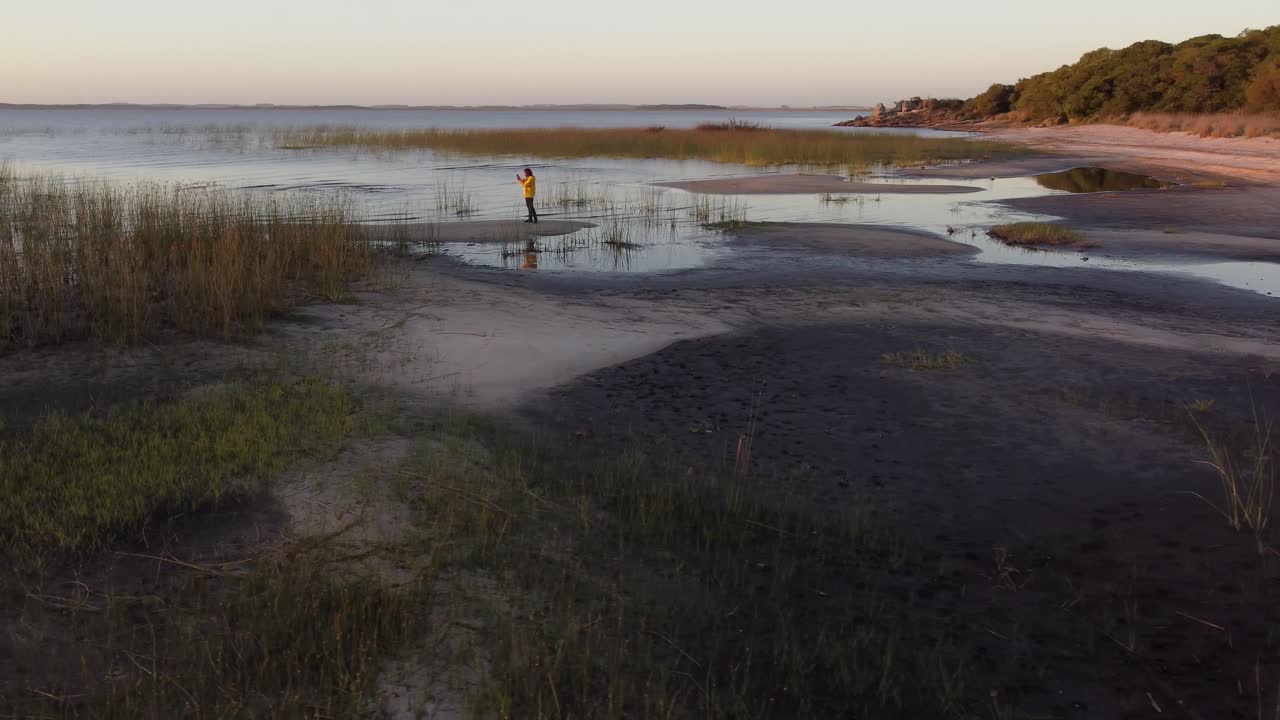 fotógrafo en la orilla de la laguna de arena al atardecer, laguna negra en uruguay