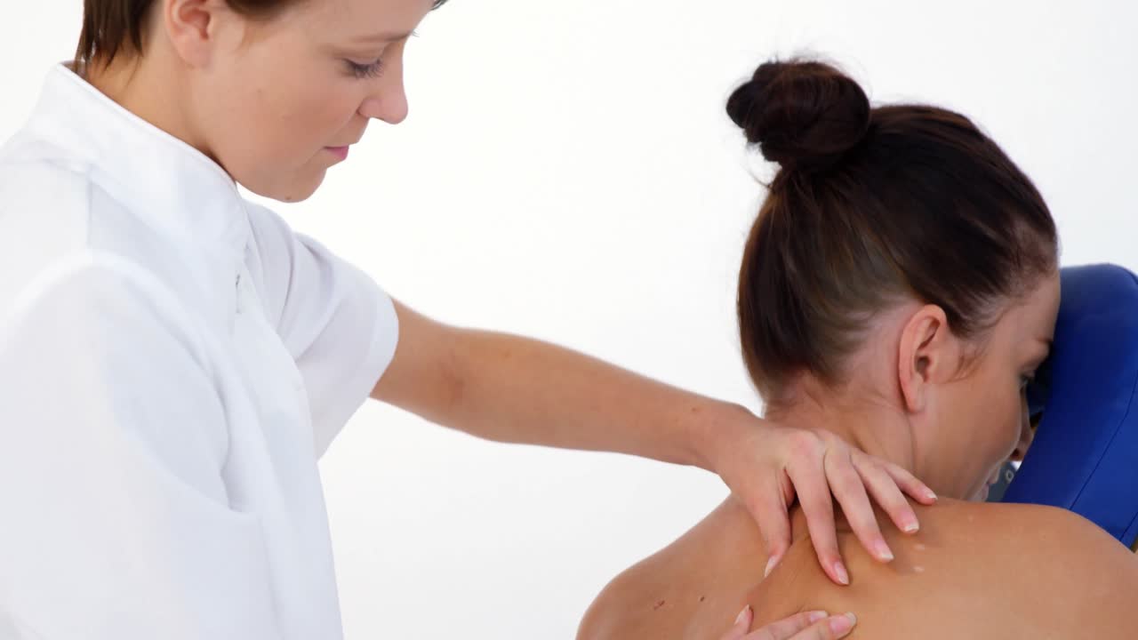 vista de perfil de una mujer terapeuta masajeando la espalda de su paciente