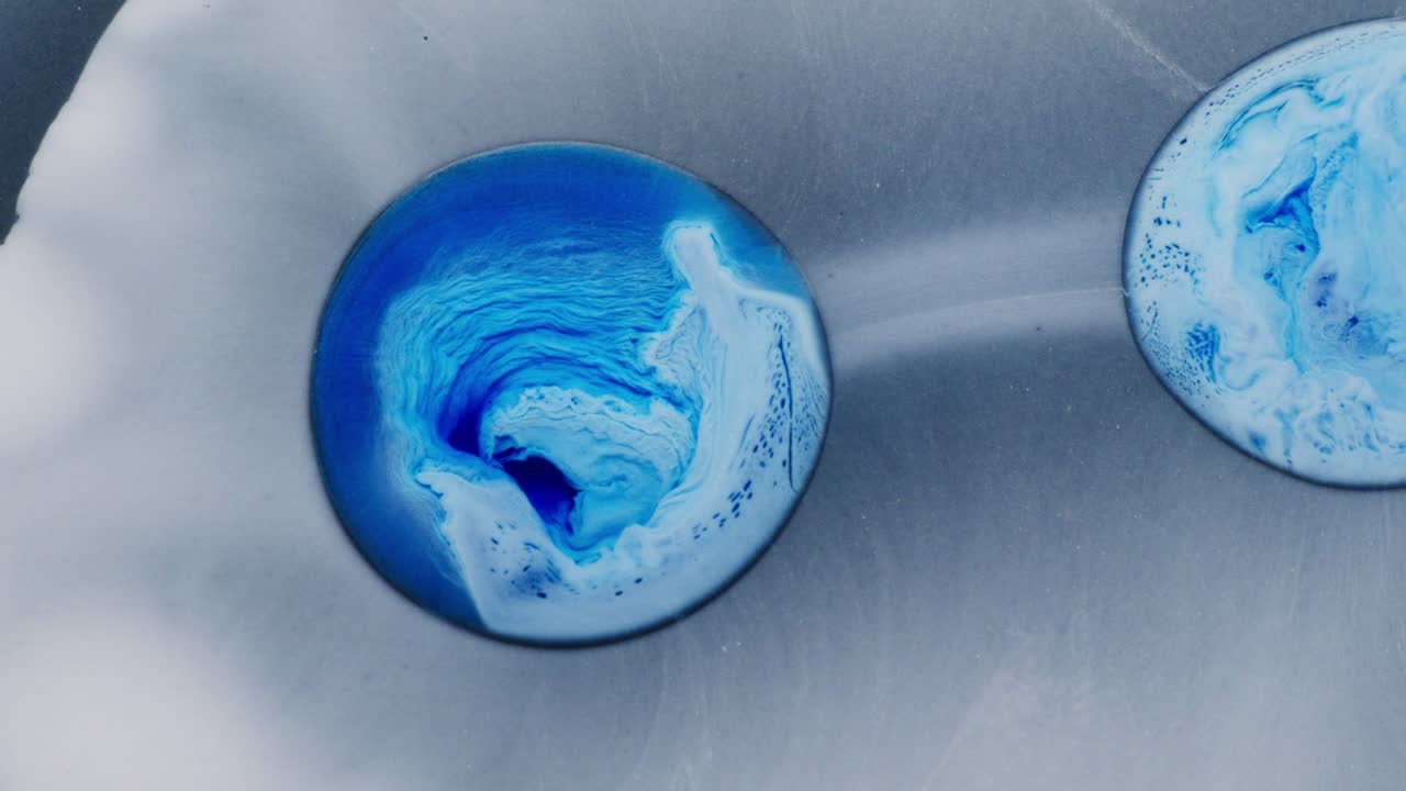 Alcoholic ink swirling in blue, macro shot of abstract texture on smooth surface