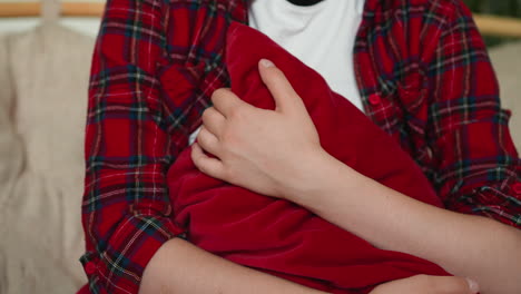 woman holding a red pillow while sitting on a couch